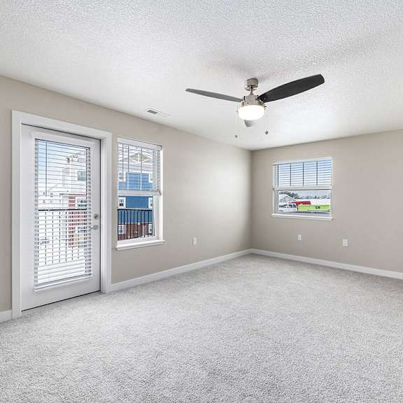 Thumbnail 5 of 15 An enlarged living room with a ceiling fan and two windows at Eagle Ridge Apartment Homes, Traverse City