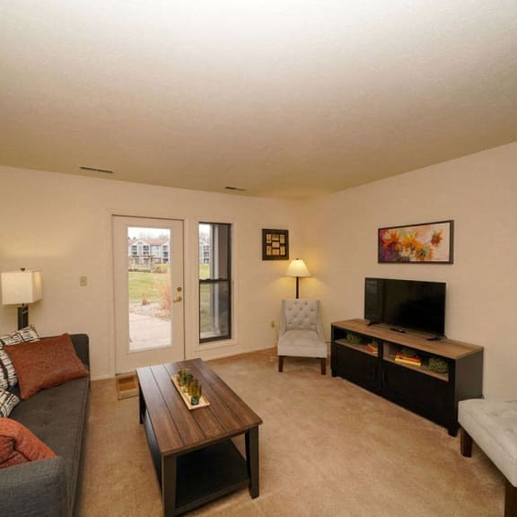 Thumbnail 3 of 10 A living room with access to a private patio at Emerald Park Apartments, Kalamazoo, MI, 49001