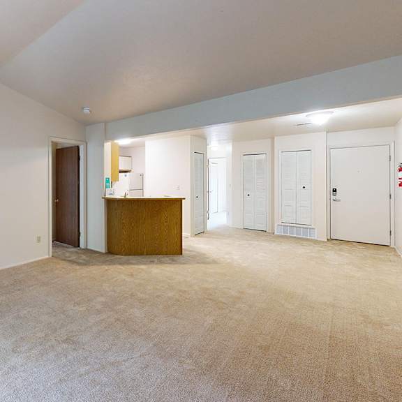 Thumbnail 5 of 10 A living room with a vaulted ceiling and plush carpeting at Emerald Park Apartments, Kalamazoo