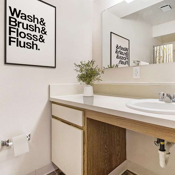 Thumbnail 11 of 17 A bathroom with a white sink and a large vanity area at Emerald Park Apartments, Kalamazoo, Michigan
