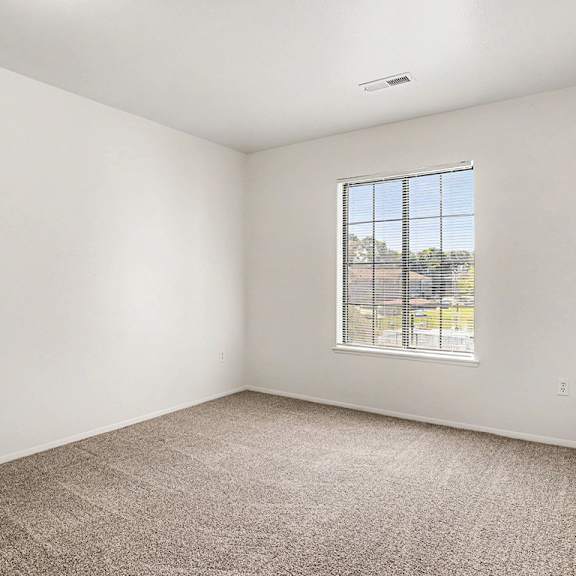Thumbnail 13 of 17 A bedroom with a carpeted floor and a window with a view at Emerald Park Apartments, Kalamazoo, Michigan