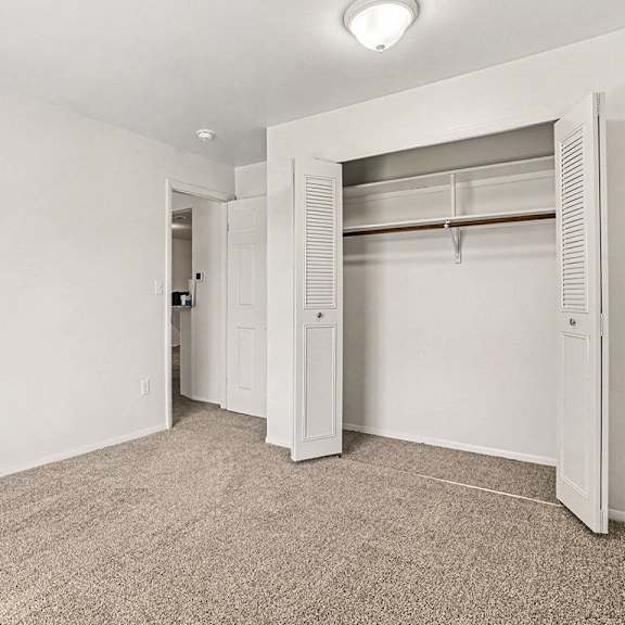Thumbnail 14 of 17 A white closet with a carpeted floor and a white door at Emerald Park Apartments, Kalamazoo, Michigan