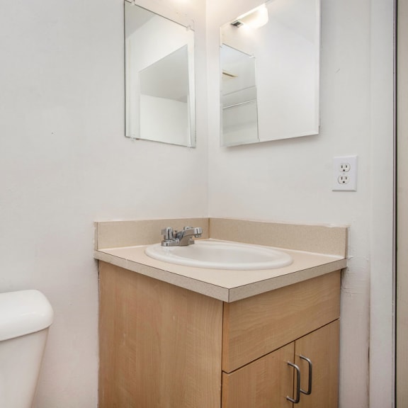Thumbnail 13 of 17 a bathroom with a sink and a toilet and a mirror at Fairlane Apartments in MI 49037