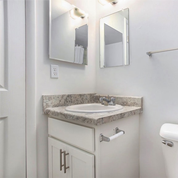 Thumbnail 15 of 17 a bathroom with a sink and a toilet and a mirror at Fairlane Apartments in Springfield, MI