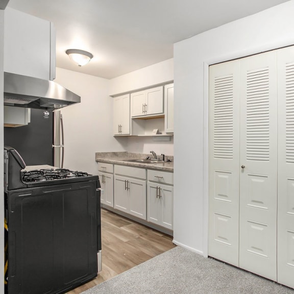 Thumbnail 8 of 17 a kitchen with white cabinets and a stove and a refrigerator at Fairlane Apartments in Springfield, MI 49037