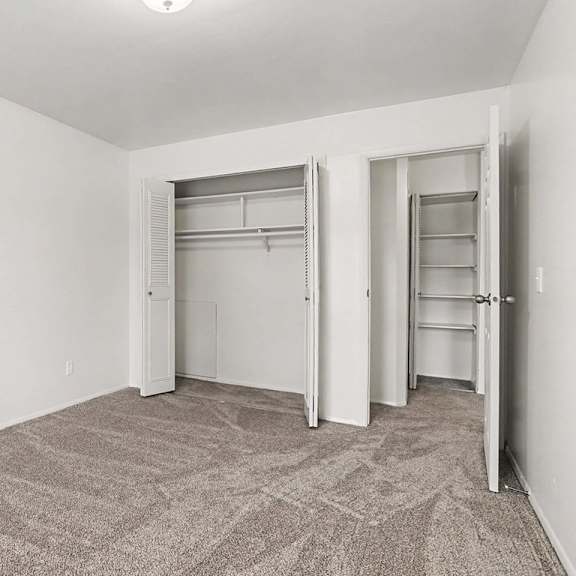 Thumbnail 17 of 17 Vacant bedroom with dual closets and shelving at Fairlane Apartments, Springfield, Michigan