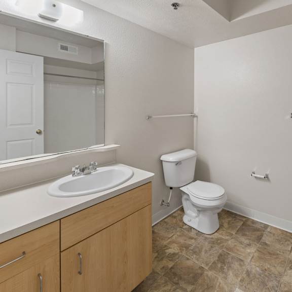Thumbnail 6 of 7 A bathroom with a toilet, sink, and mirror at Fieldstream Apartment Homes, Iowa