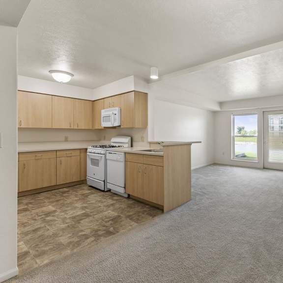 Thumbnail 3 of 7 A kitchen with wooden cabinets and a white dishwasher at Fieldstream Apartment Homes, Iowa
