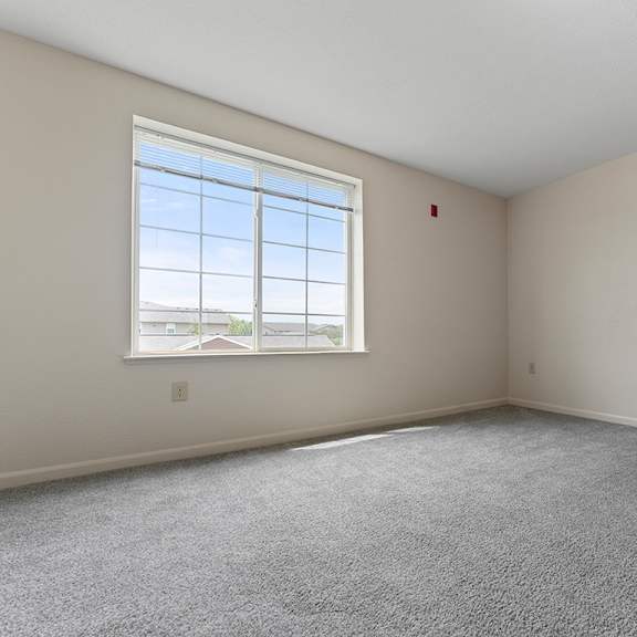Thumbnail 15 of 18 A bedroom with a large window and carpeted floor at Fieldstream Apartment Homes, Iowa