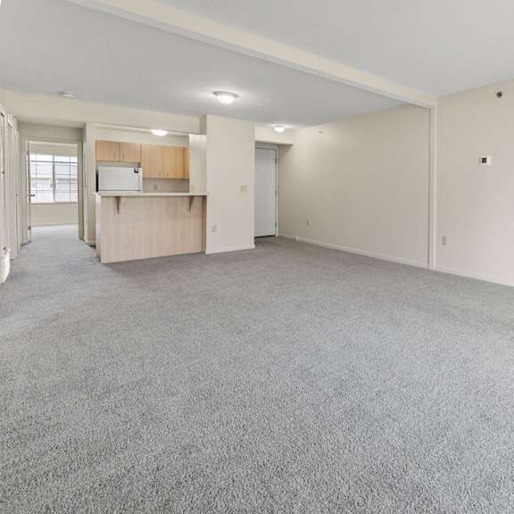 Thumbnail 6 of 18 A large, empty dining room with a grey carpet at Fieldstream Apartment Homes, Iowa