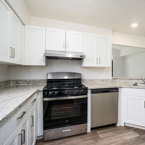 Thumbnail 7 of 12 A kitchen with a stove and a dishwasher at Foxwood and The Hermitage in Portage, MI