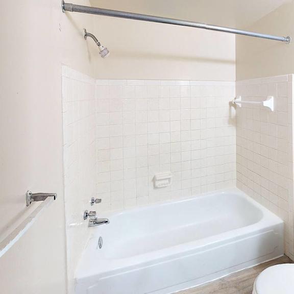Thumbnail 12 of 14 A full bathroom with a bath tub, toilet, and shower at Glen Oaks Apartments, Michigan, 49442