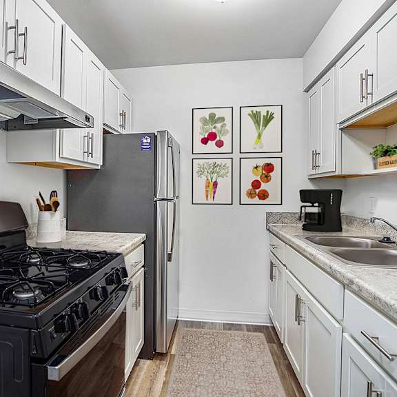 Thumbnail 8 of 12 A kitchen with a stainless steel stove top and a refrigerator at Glen Oaks Apartments, Michigan, 49442