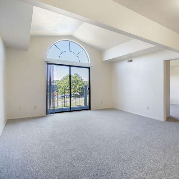Thumbnail 4 of 14 A spacious living room with a large arched window and a view of trees outside at Glenn Valley Apartments, Michigan, 49015