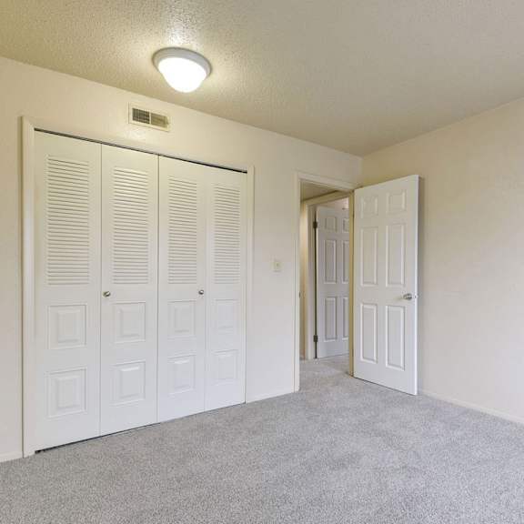 Thumbnail 12 of 12 A bedroom with a large closet and grey carpet at Granada Apartments, Jackson, 49202
