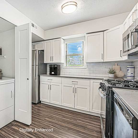 Thumbnail 5 of 10 A white kitchen with hard surface floors and a washer and dryer at Green Ridge Apartments, Grand Rapids, 49544