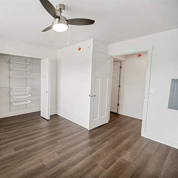 Thumbnail 19 of 19 A bedroom with a ceiling fan and a walk-in closet with wardrobe organizers at The Grove Apartment Homes in Lincoln, NE