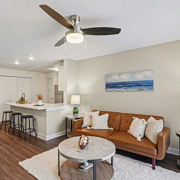 Thumbnail 7 of 19 A living room with a brown couch and a ceiling fan at The Grove Apartment Homes, Nebraska