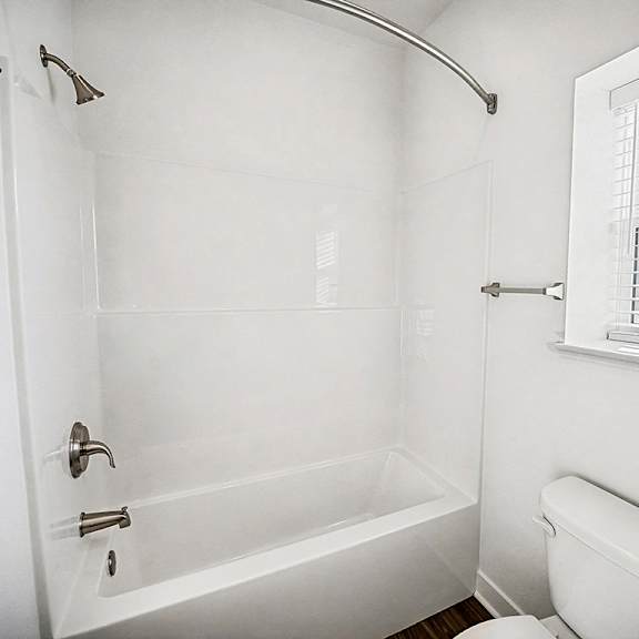 Thumbnail 10 of 13 A white bathroom with a toilet and a bathtub at The Grove Apartment Homes in Lincoln, NE