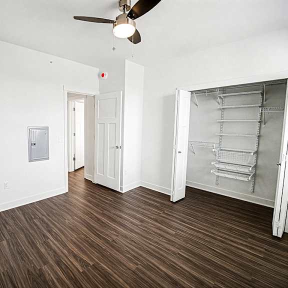 Thumbnail 12 of 13 A bedroom with a ceiling fan and a walk-in closet with wardrobe organizers at The Grove Apartment Homes in Lincoln, NE