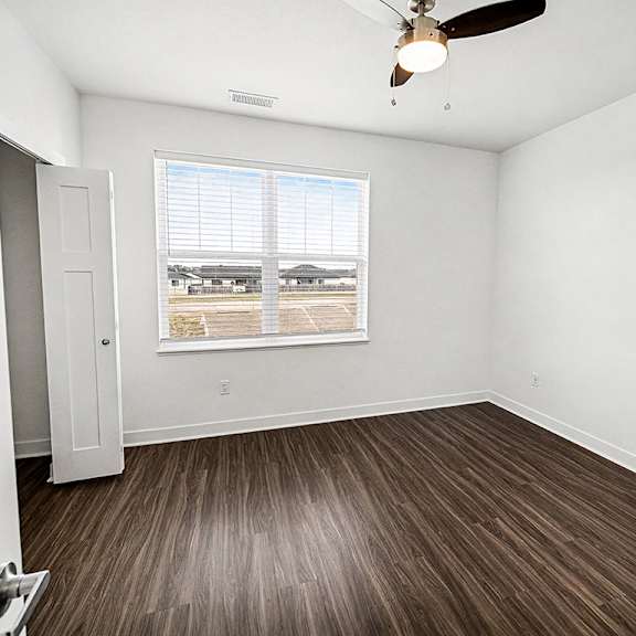 Thumbnail 13 of 13 A bedroom with a ceiling fan, a large closet and window at The Grove Apartment Homes in Lincoln, NE
