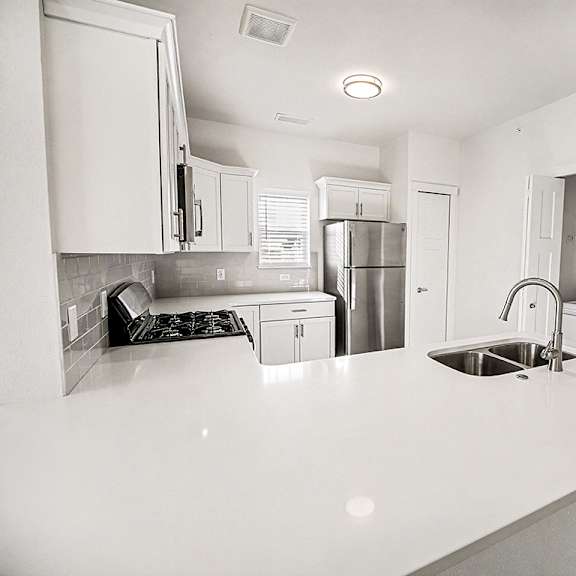 Thumbnail 7 of 13 A kitchen with white countertops and a window at The Grove Apartment Homes in Lincoln, NE