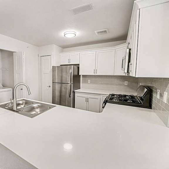 Thumbnail 12 of 19 A kitchen with white cabinets and a washer/dryer at The Grove Apartment Homes in Lincoln, NE