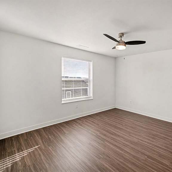 Thumbnail 14 of 14 A spacious bedroom with a ceiling fan and a large window at The Grove Apartment Homes in Lincoln, NE