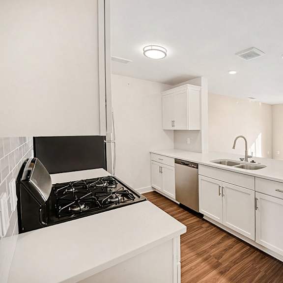 Thumbnail 7 of 14 A modern kitchen with white cabinets and a breakfast bar at The Grove Apartment Homes in Lincoln, NE