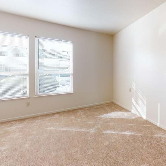 Thumbnail 13 of 13 A bedroom with a carpeted floor and a window with blinds at Gull Prairie/Gull Run Apartments and Townhomes, Kalamazoo, Michigan