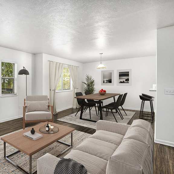 Thumbnail 4 of 18 A living room with a grey couch, a wooden coffee table, and a dining table with chairs at Gull Prairie/Gull Run Apartments and Townhomes, Kalamazoo, MI