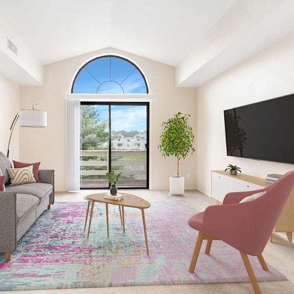 Thumbnail 4 of 7 A living room with a cathedral ceiling, grey couch, a pink chair, a small table, a flat screen TV, and sliding glass doors to a balcony at Gull Prairie/Gull Run Apartments and Townhomes, Michigan