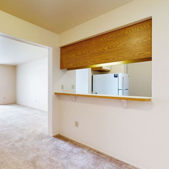Thumbnail 6 of 15 an empty living room with a refrigerator in it at Hampton Lakes Apartments in Walker, MI 49534