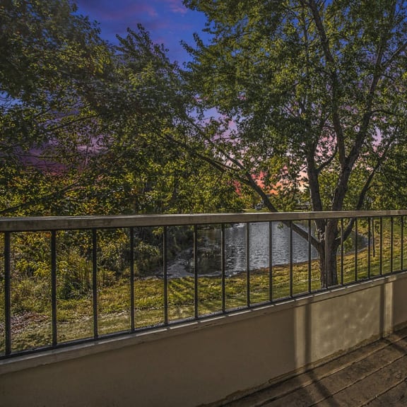 Thumbnail 6 of 14 a balcony with a view of a pond and trees at Hampton Lakes Apartments, Michigan, 49534