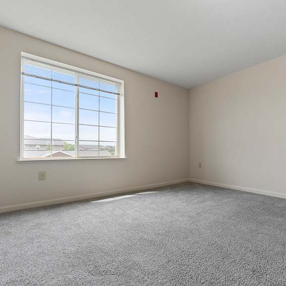 Thumbnail 16 of 18 A bedroom with a large window and carpeted floor at Hunters Pond Apartment Homes, Champaign, IL, 61820