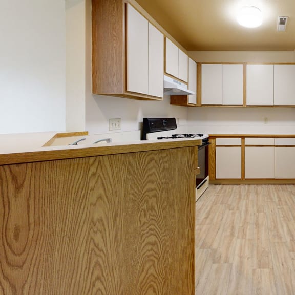 Thumbnail 4 of 6 an empty kitchen with wood flooring and white cabinets at Irish Hills Apartments, South Bend, 46614