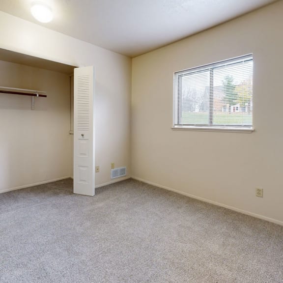 Thumbnail 7 of 7 an empty bedroom with a closet and a window at Irish Hills Apartments, South Bend, Indiana