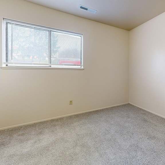 Thumbnail 6 of 6 A bedroom with a window and carpeted floor at Irish Hills Apartments, South Bend, Indiana