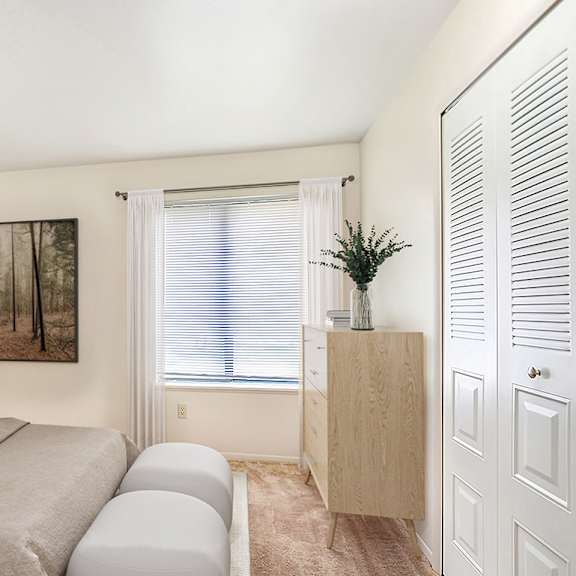 Thumbnail 11 of 13 A bedroom with a bed, a nightstand, a cabinet, and a closet at Irish Hills Apartments, South Bend, Indiana