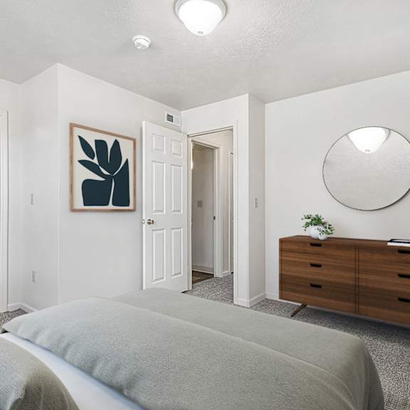 Thumbnail 10 of 10 A bedroom with a walk-in closet, grey bed and a wooden dresser at Liberty Mills Apartments, Fort Wayne