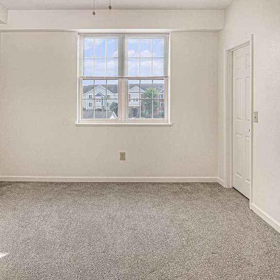 Thumbnail 15 of 21 A bedroom with a large window, carpeted floor and a door to a walk-in closet at Limestone Creek Apartment Homes, Madison, AL