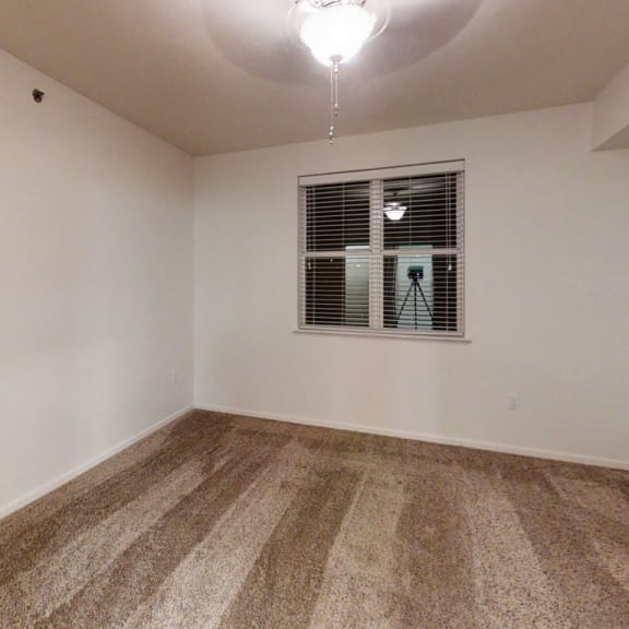 Thumbnail 10 of 12 an empty living room with carpet and a window  at Lynbrook Apartment Homes and Townhomes, Elkhorn, NE, 68022