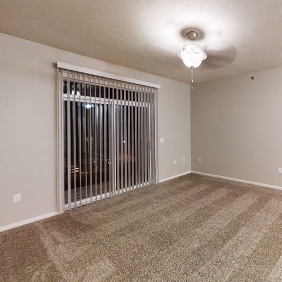 Thumbnail 6 of 12 an empty living room with a window and a ceiling fan  at Lynbrook Apartment Homes and Townhomes, Elkhorn, NE, 68022