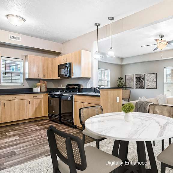 Thumbnail 3 of 15 A dining room and kitchen with wooden cabinets and a black stove at Lynbrook Apartments and Townhomes, Elkhorn, NE, 68022.
