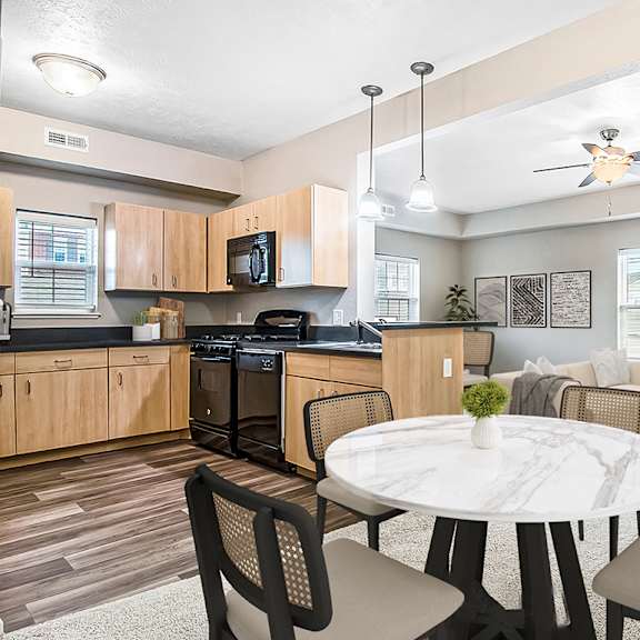 Thumbnail 3 of 13 A dining room and kitchen with wooden cabinets and a black stove at Lynbrook Apartments and Townhomes, Elkhorn, NE, 68022.
