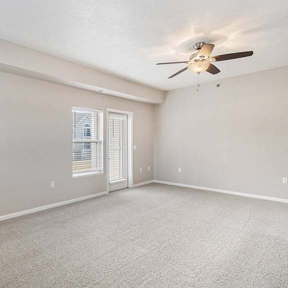 Thumbnail 10 of 15 An enlarged living room with a ceiling fan and access to a private patio at Lynbrook Apartments and Townhomes, Elkhorn, NE, 68022