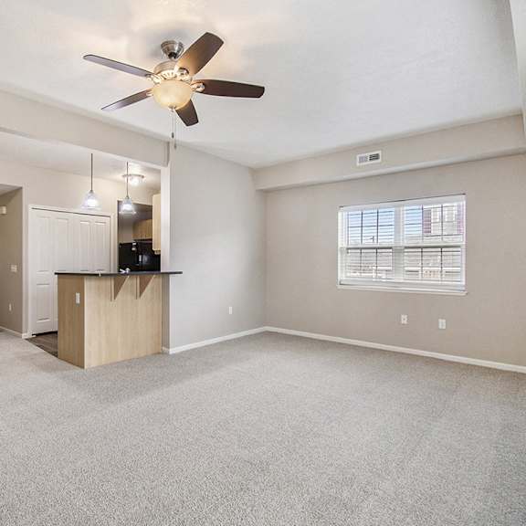 Thumbnail 11 of 15 An end style living room with a carpeting, a ceiling fan, and a window with blinds at Lynbrook Apartments and Townhomes, Elkhorn, NE, 68022