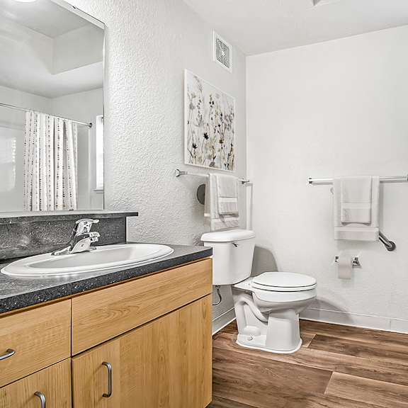Thumbnail 11 of 13 A bathroom with a toilet, sink, and a window at Lynbrook Apartments and Townhomes, Elkhorn, NE, 68022