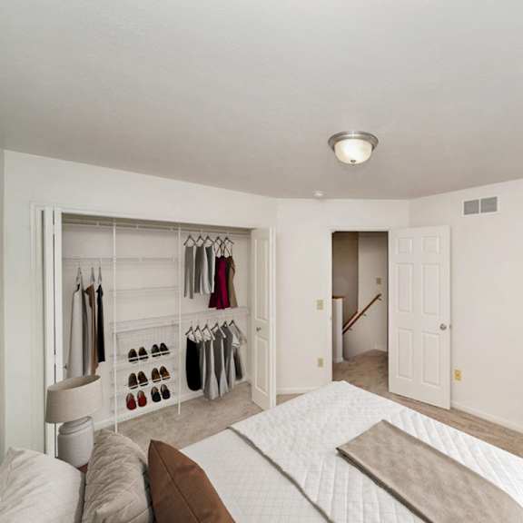 Thumbnail 9 of 15 A bedroom with a bed, and a closet with wardrobe organizers at Lynbrook Apartments and Townhomes, Elkhorn, 68022