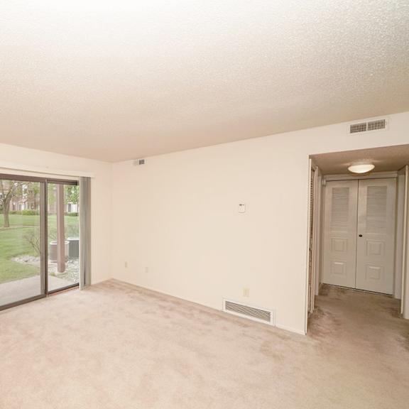 Thumbnail 3 of 9 an empty living room with a door to a patio at Madeira Apartments, Kalamazoo, 49001